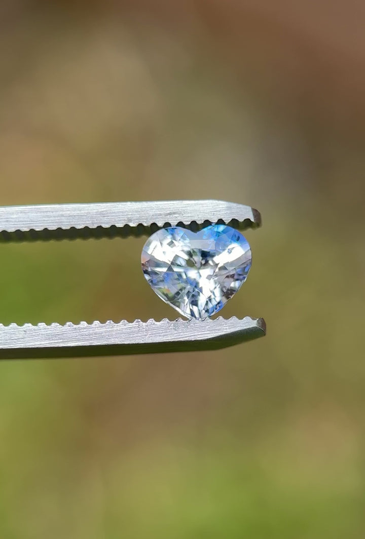 Close-up video of a heart cut parti sapphire rotating in tweezers, reflecting brilliant blue and clear color zoning – 1.30ct heated gem from Sakaraha, Madagascar.
