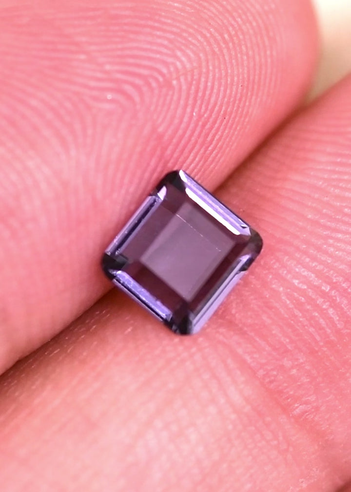Close-up video of 1.01 carat Sri Lankan purple spinel portrait cut in tweezers, precision faceting and lavender pink tones visible as gemstone moves in studio lighting