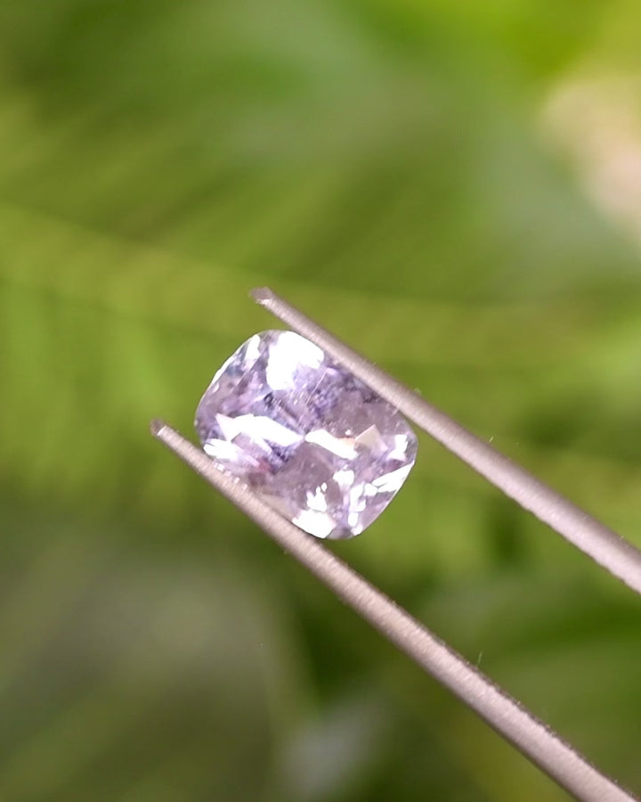 Video of 1.65CT sapphire rotating in gemstone tweezers, capturing violet, purple, and pink color transitions and brilliance of the cushion cut, natural untreated sapphire from Sakaraha, Madagascar.