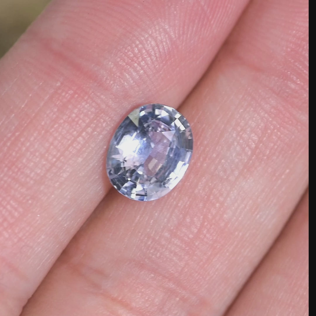 Video showing a 2.25 carat gray pink sapphire in hand under natural light, oval mix cut Sri Lanka sapphire revealing color shifts and brilliance