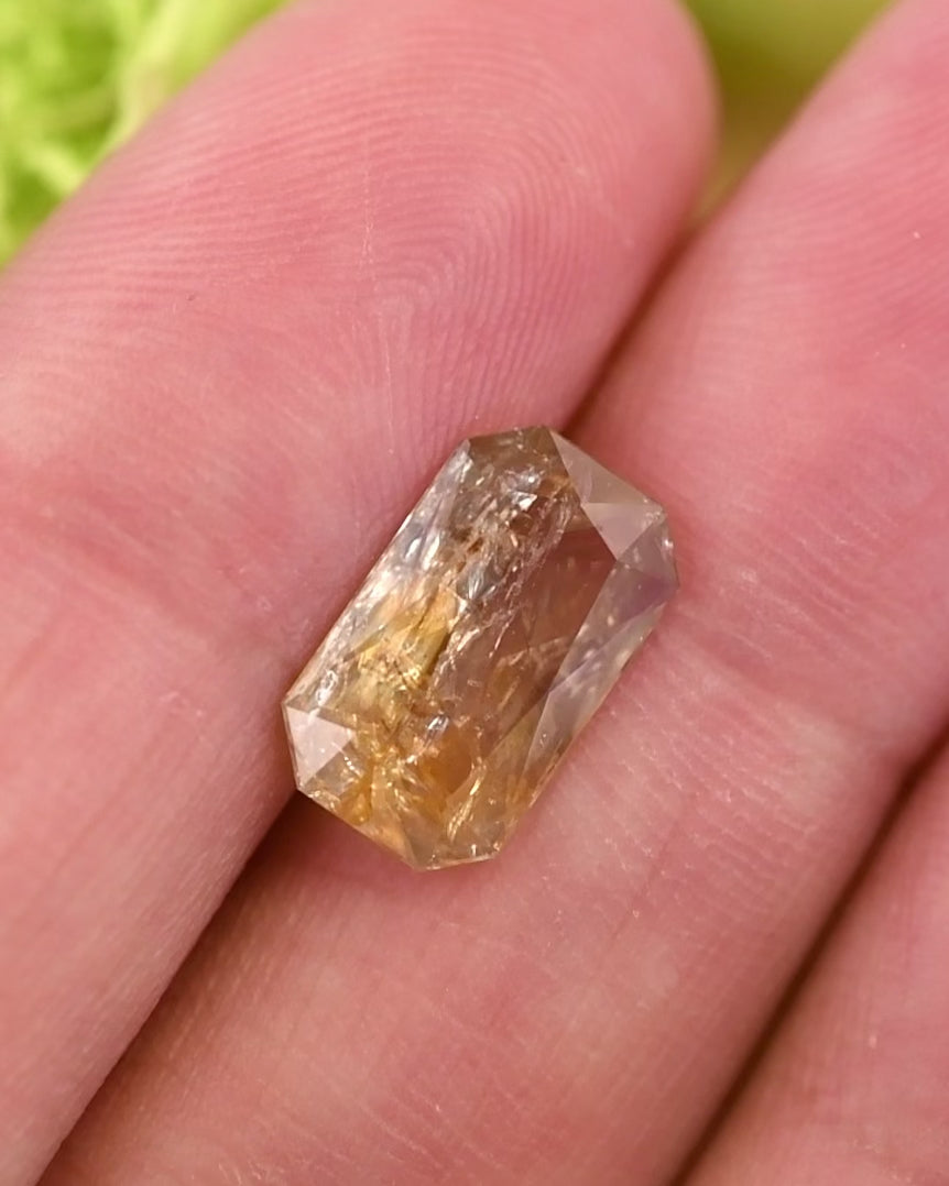 Macro video of 3.50 carat sapphire rotating gently, revealing bright yellow and orange hues and intricate facets of its modified radiant cut, unheated gemstone from Umba River Valley, Tanzania.