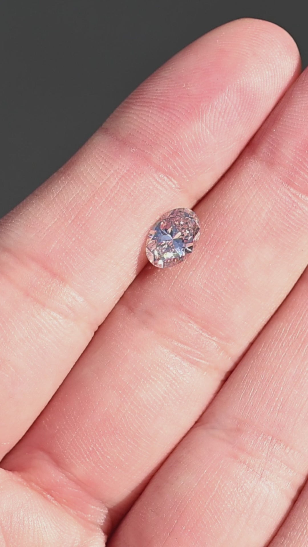1.07ct natural champagne oval brilliant cut diamond from Canada rotating on fingertips under direct sunlight.