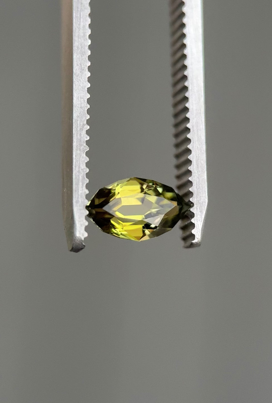Video of a 0.94-carat olive green tanzanite being rotated under bright light to show the custom antique style cut, natural color, and brilliance. Untreated Tanzanite from Merelani Hills displaying clarity and faceting detail.