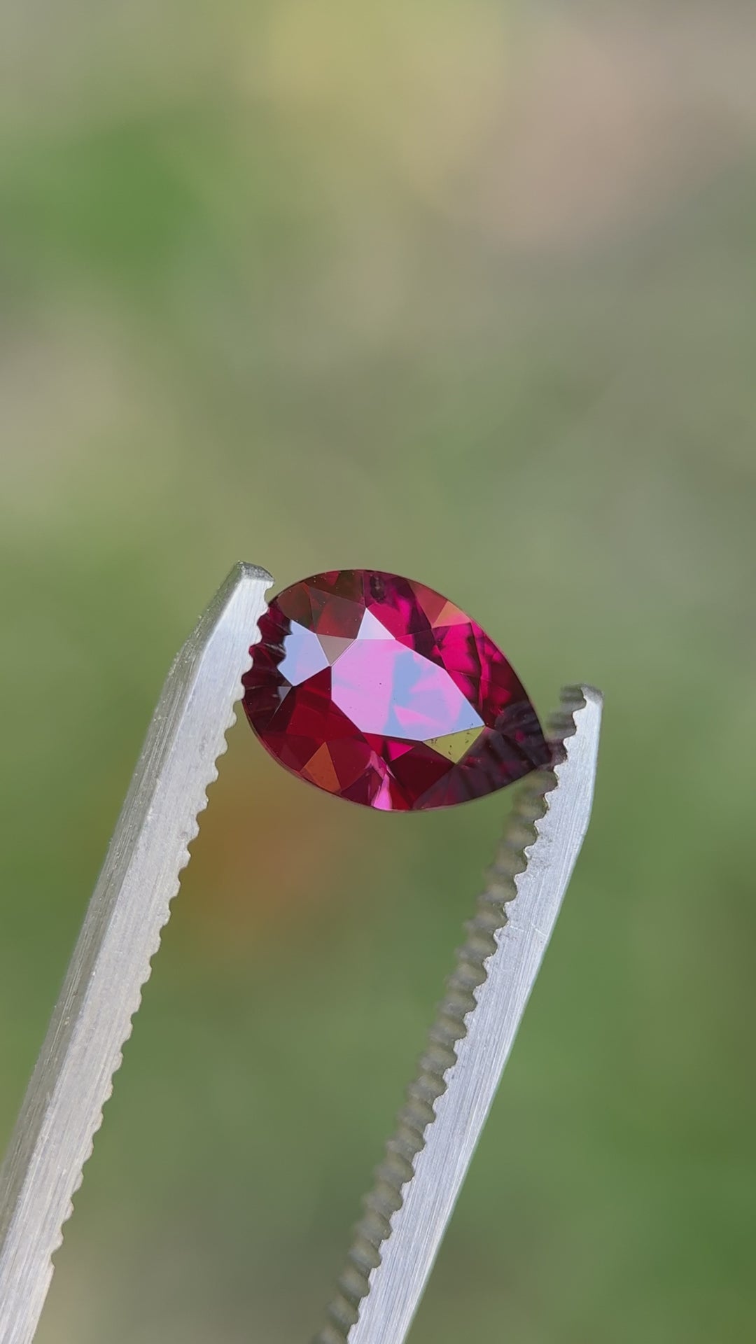 Rotating view of 2.40 carat garnet in natural light, showing shifting tones of vivid raspberry and rose red in precision cut
