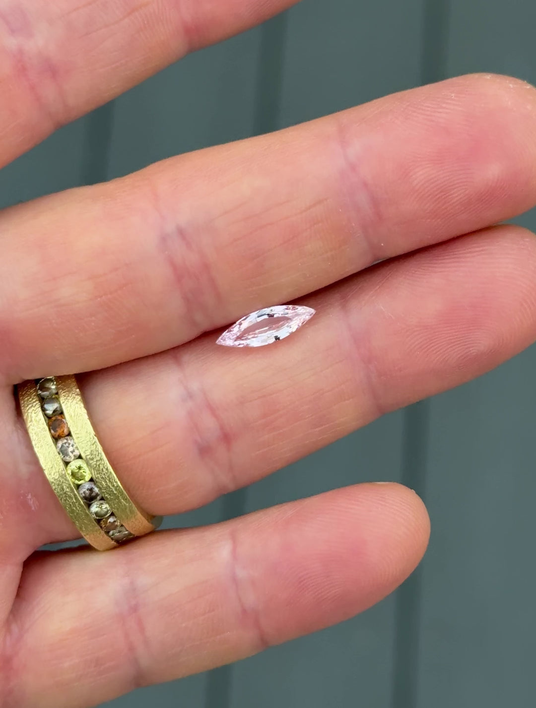 Close-up video of 1.03 carat blush pink sapphire resting on fingertip, moving under natural light to highlight the luster, fine polish, and delicate hue of the precision marquise mixed cut, heated sapphire from Sakaraha, Madagascar.