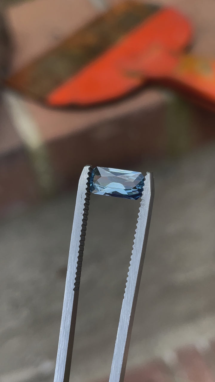 A rotating view of a 1.26-carat blue sapphire featuring an elongated geometric cushion cut. Its precise cuts highlight the vibrant blue hue, captured against a neutral background. The sapphire is untreated and sourced from the Umba River, Tanzania.