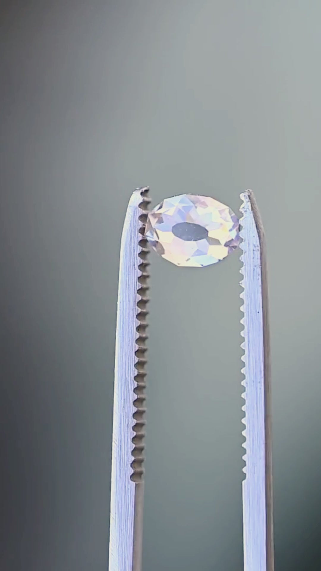 1.08 carat oval Mughal cut diamond rotated between jeweler’s tweezers, showing its elongated outline, broad antique-style facets and dimensional profile.