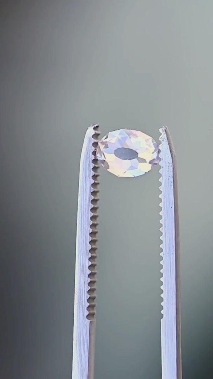 1.08 carat oval Mughal cut diamond rotated between jeweler’s tweezers, showing its elongated outline, broad antique-style facets and dimensional profile.