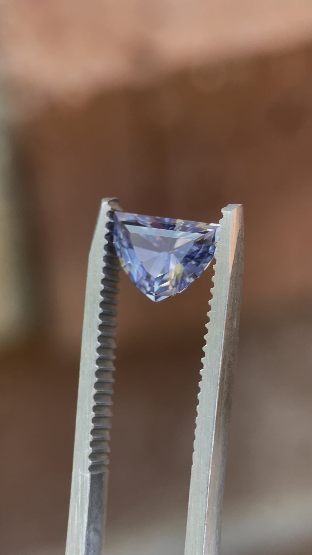 Rotating view of a 1.66ct Sri Lanka sapphire, capturing its shifting periwinkle and pink tones under natural light.