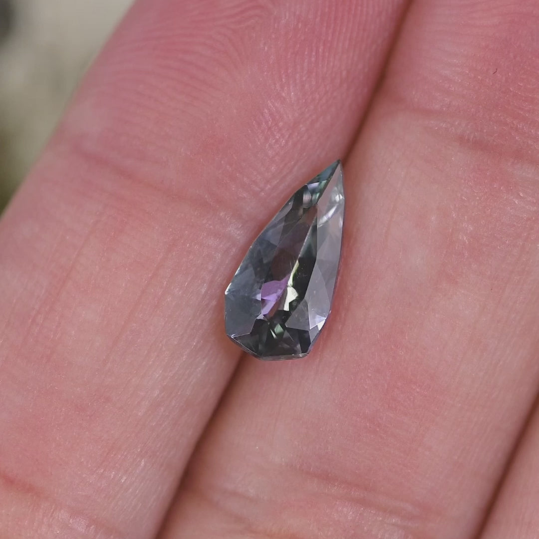 1.53 carat blue teal violet Tanzanite pear rotating under natural light, custom geometric faceted gemstone from Merelani Hills Tanzania showing vivid color shift and sparkle for custom jewelry