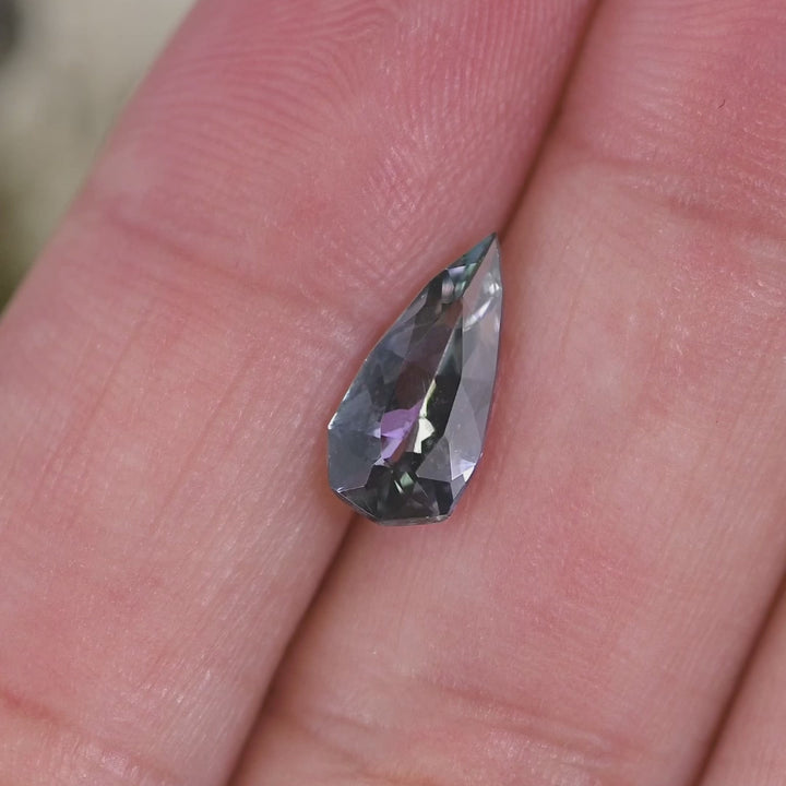 1.53 carat blue teal violet Tanzanite pear rotating under natural light, custom geometric faceted gemstone from Merelani Hills Tanzania showing vivid color shift and sparkle for custom jewelry