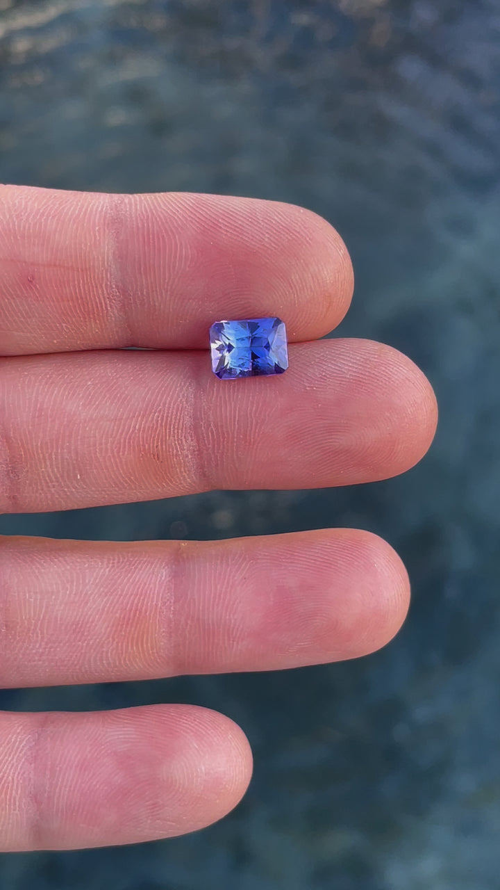 A radiant cut Tanzanite gemstone with vivid blue and ultra violet colors, weighing 3.57 carats, showcased in a detailed video.