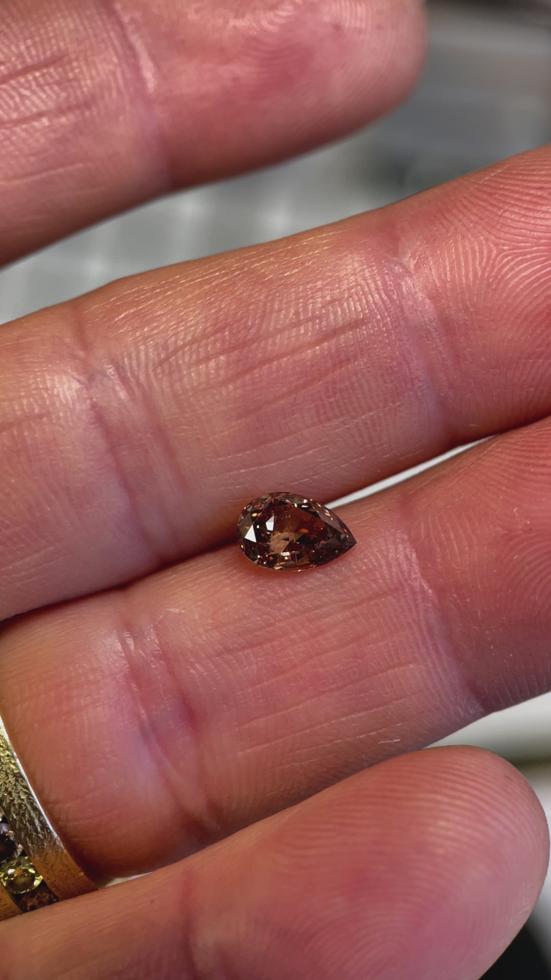 Close-up video of a 1.01-carat pear-cut Fancy Dark Orangy Brown diamond, revealing its intricate faceting and light reflection.