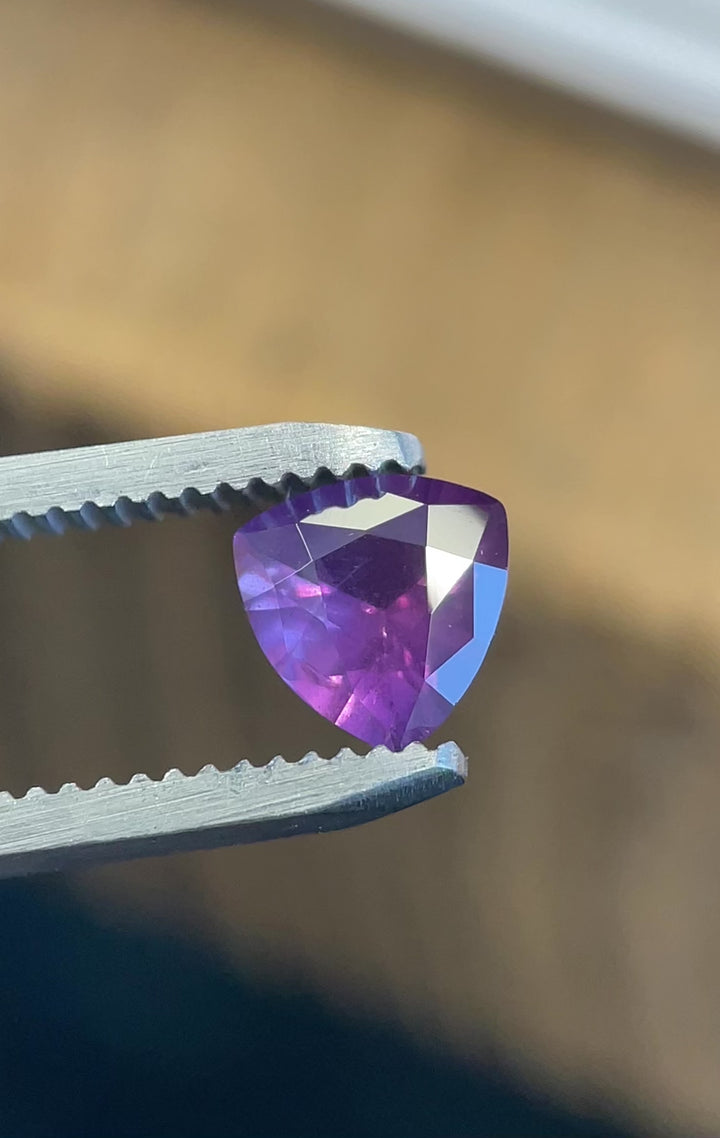 Rotating video of a custom trillion cut 0.94ct pink-purple sapphire from the Umba River, highlighting its natural untreated beauty and sparkle.