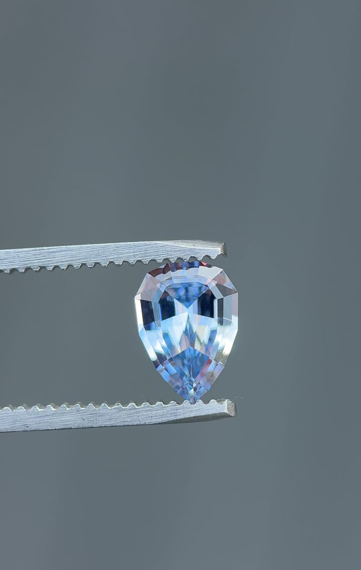 360-degree rotation of a 1.67ct unheated Sri Lankan sapphire in powder blue, captured in tweezers to highlight geometric pear brilliant cut sparkle