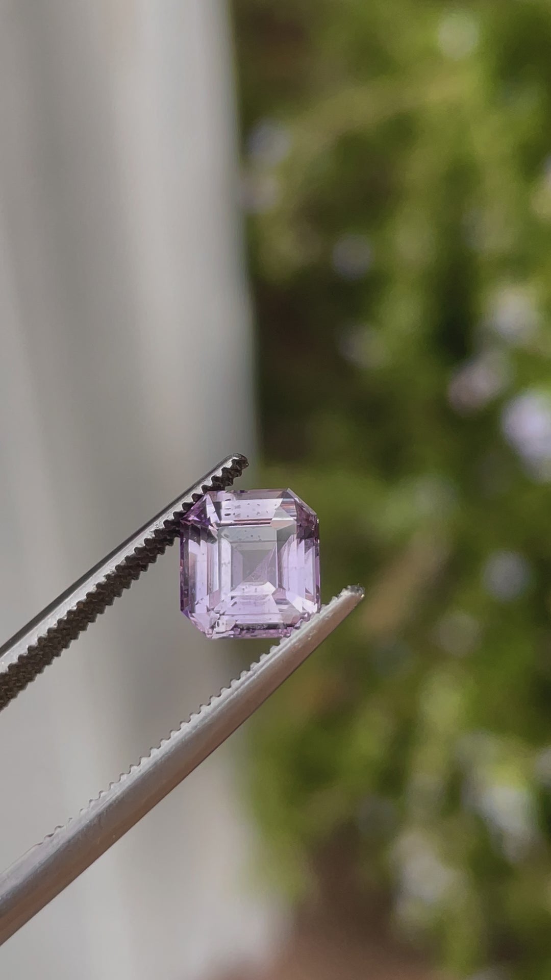 A 2.60-carat purple and pink sapphire with a modified Asscher cut slowly rotates in natural light, showing the stone’s clean facets and brilliant color play. The untreated, no-heat sapphire is from Sri Lanka and has dimensions of 7.71mm by 7.25mm by 4.97mm.