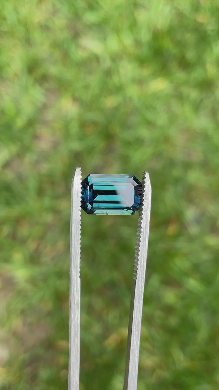 Rotating view of a 5.85 carat Gombe sapphire displaying intense peacock blue and teal color in an emerald step cut.