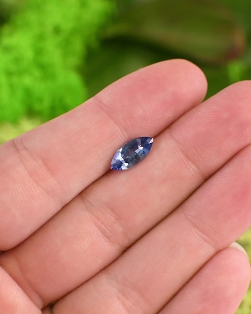 Close-up video of 1.57 carat vivid blue sapphire on fingertip, highlighting reflections, brilliance, and intense blue tone in daylight, precision marquise mixed cut, untreated sapphire from Sakaraha, Madagascar.