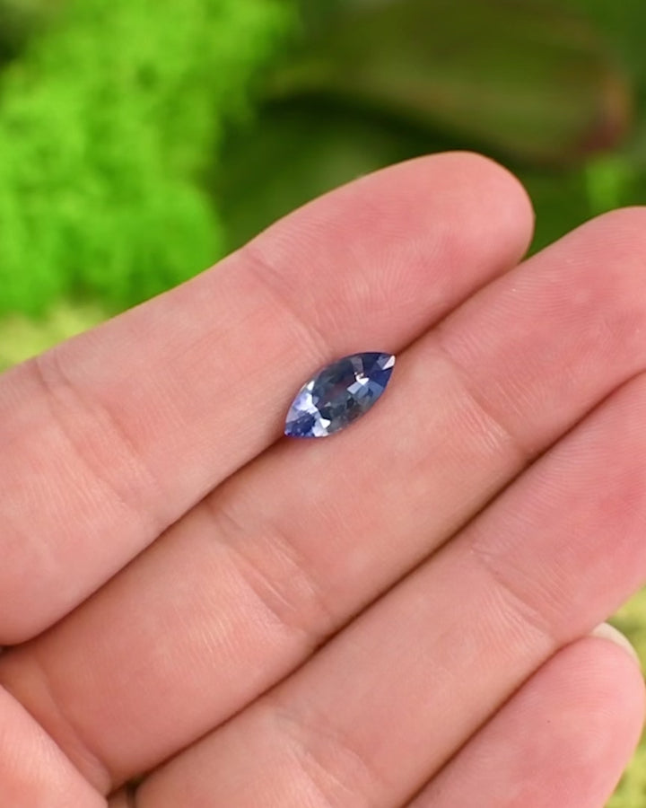 Close-up video of 1.57 carat vivid blue sapphire on fingertip, highlighting reflections, brilliance, and intense blue tone in daylight, precision marquise mixed cut, untreated sapphire from Sakaraha, Madagascar.