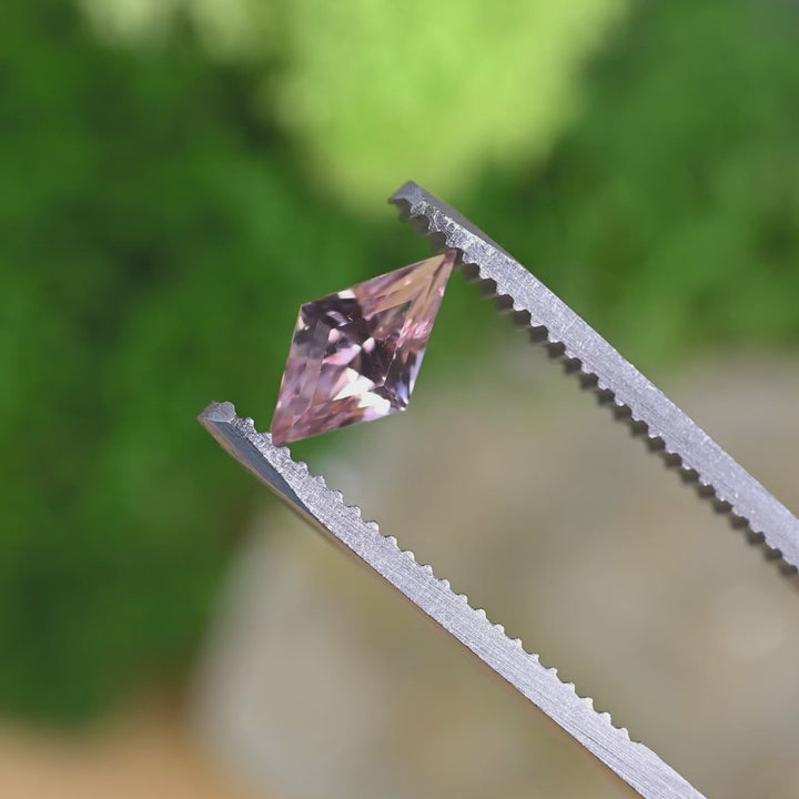 Loose salmon peach pink sapphire from Madagascar turning in light, revealing the geometric kite mix cut and natural pastel color tones.