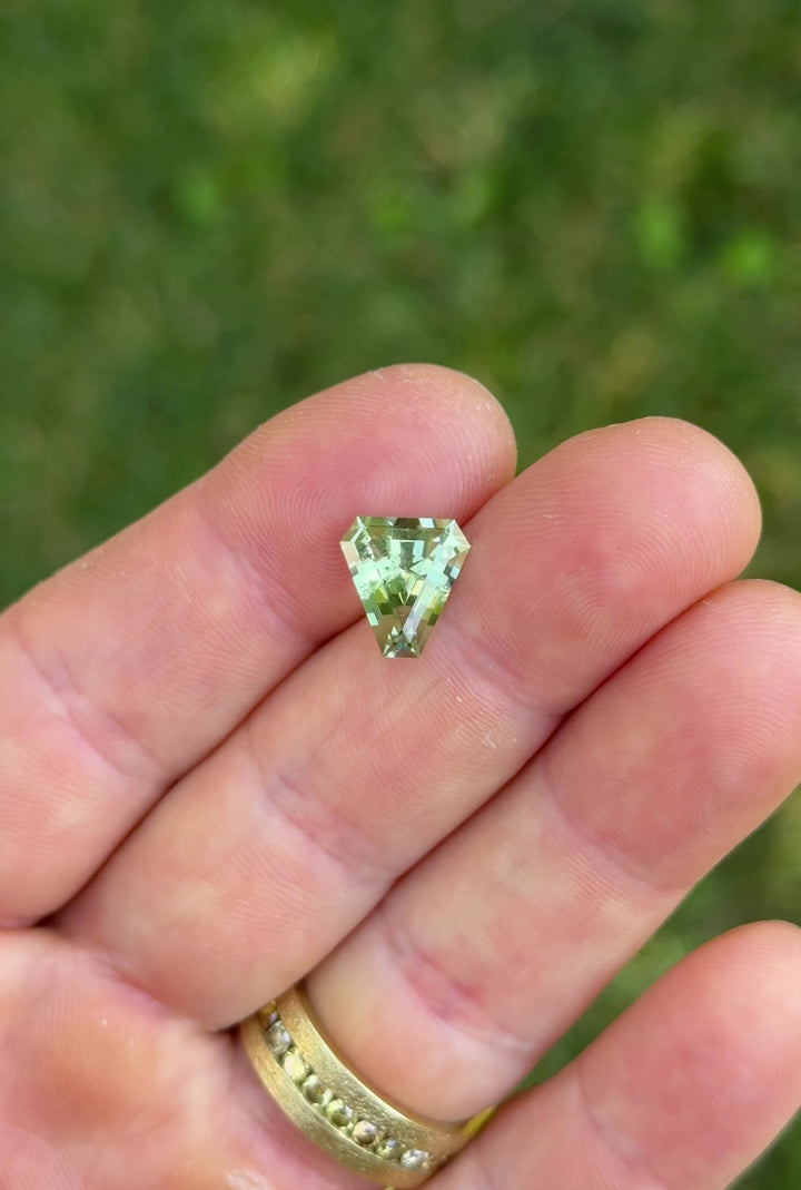 Macro close-up video of 3.26CT mint green tourmaline gemstone turning in tweezers, revealing precise step cut symmetry and pastel brilliance, ethically mined in Congo, Africa.
