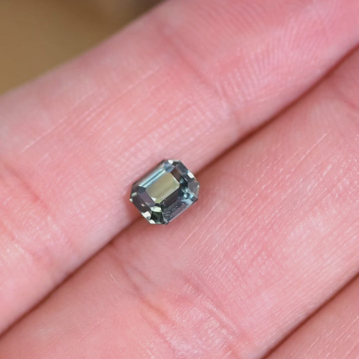 Rotating loose blue green sapphire from Sakaraha, Madagascar showing the reflective step facets and shifting teal tones of the emerald cut.
