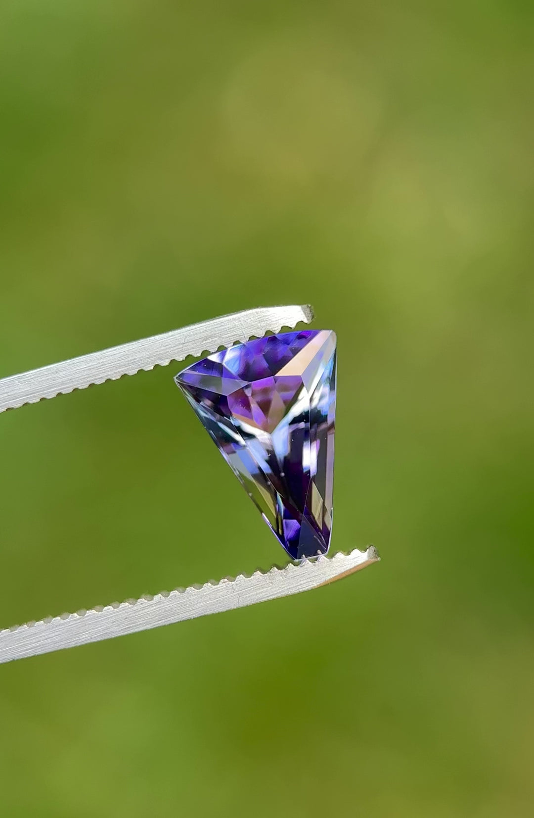 360° video of custom tapered fan cut Tanzanite showing vibrant teal and purple mermaid tones in natural lighting