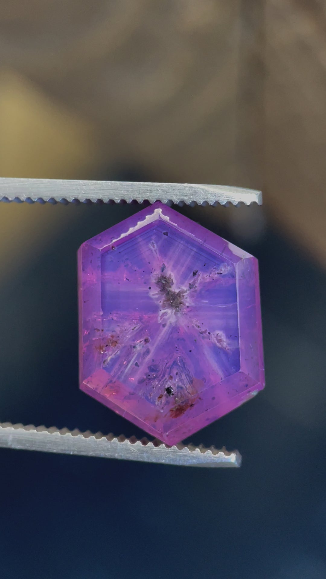 A rotating view of a 19.62-carat pink and purple Afghan sapphire, showcasing its hexagon portrait cut and stunning natural inclusions under different lighting.