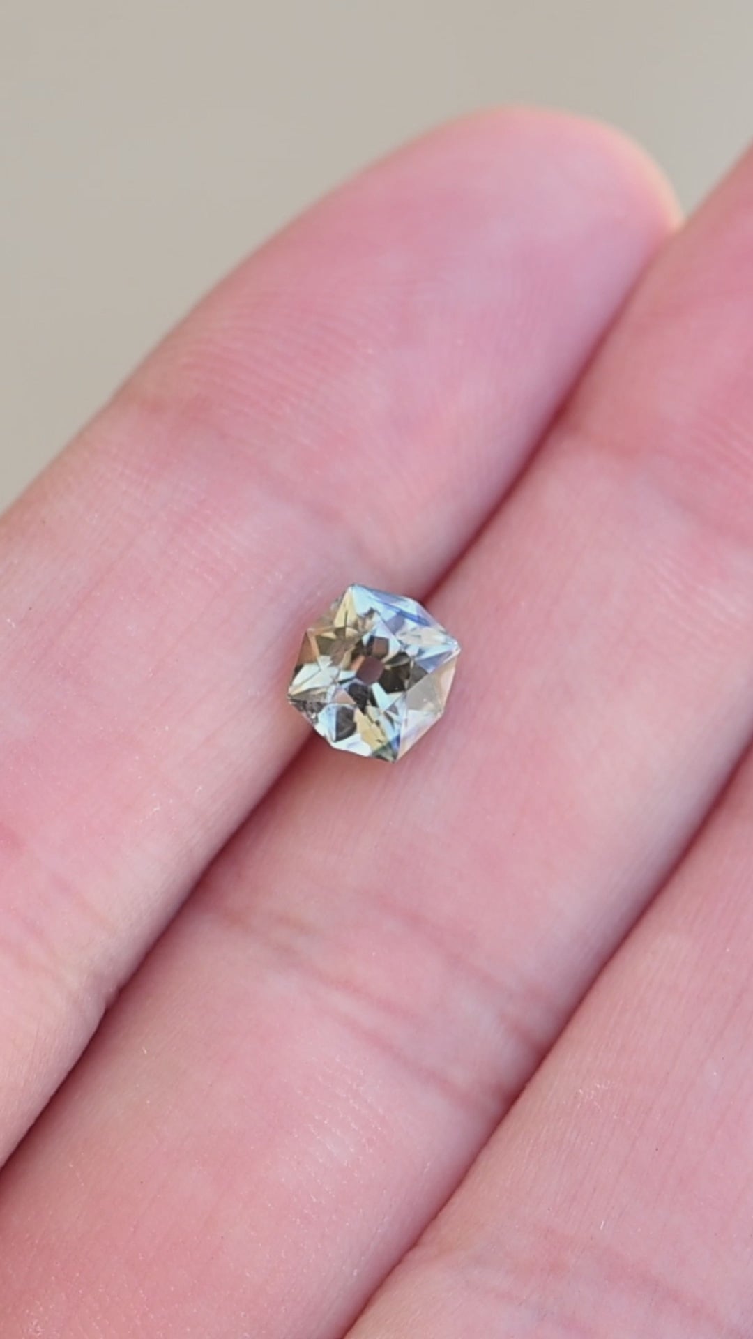 1.62ct teal yellow parti custom old mine cushion cut sapphire rotating on finger tips under natural light.