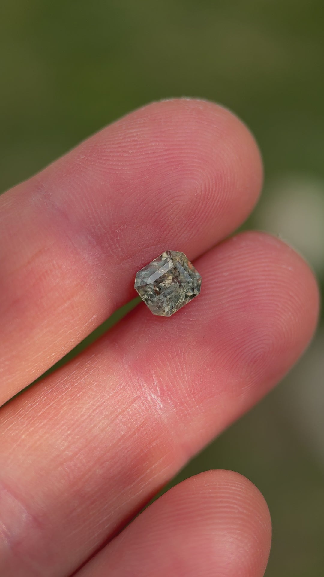 Rotation video of 1.67 carat color-change sapphire from Umba River, Tanzania, showing transition from earthy green to grayish red tones in a custom squared emerald cut, untreated and natural gemstone.