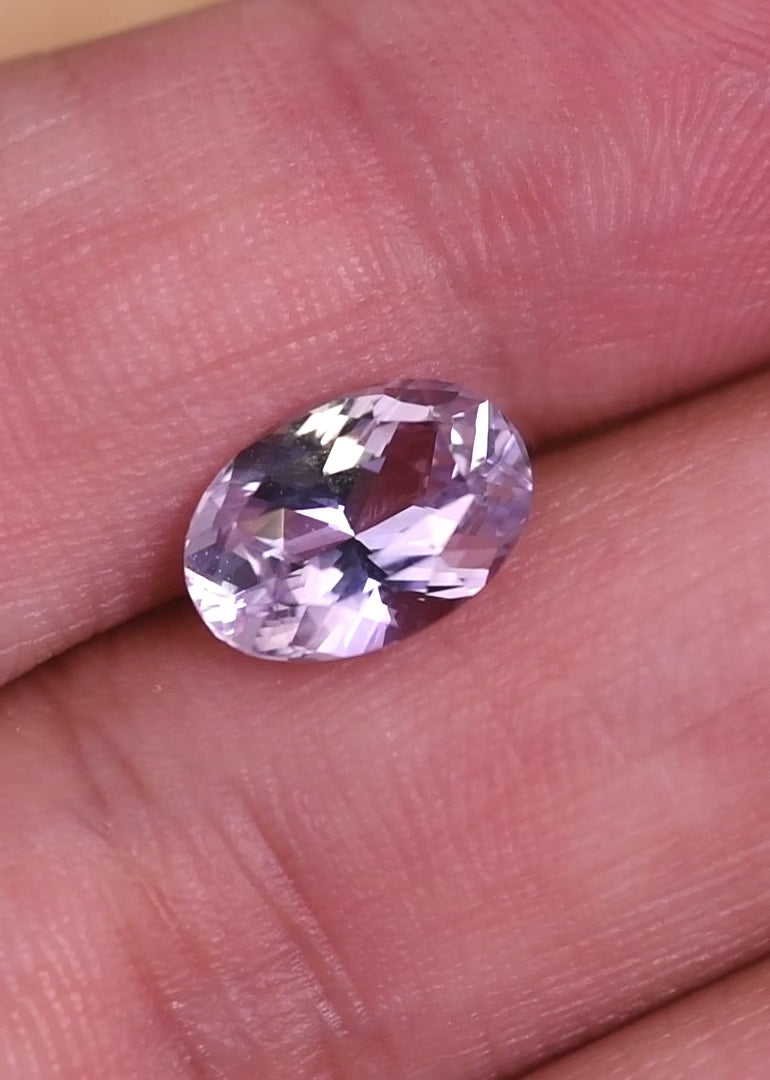 Loose lavender pink purple sapphire from Madagascar rotating under light displaying the sparkle and facet reflections of the precision oval mixed cut.