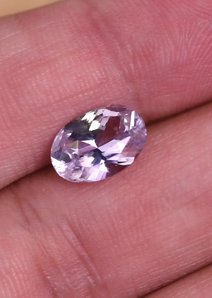 Loose lavender pink purple sapphire from Madagascar rotating under light displaying the sparkle and facet reflections of the precision oval mixed cut.