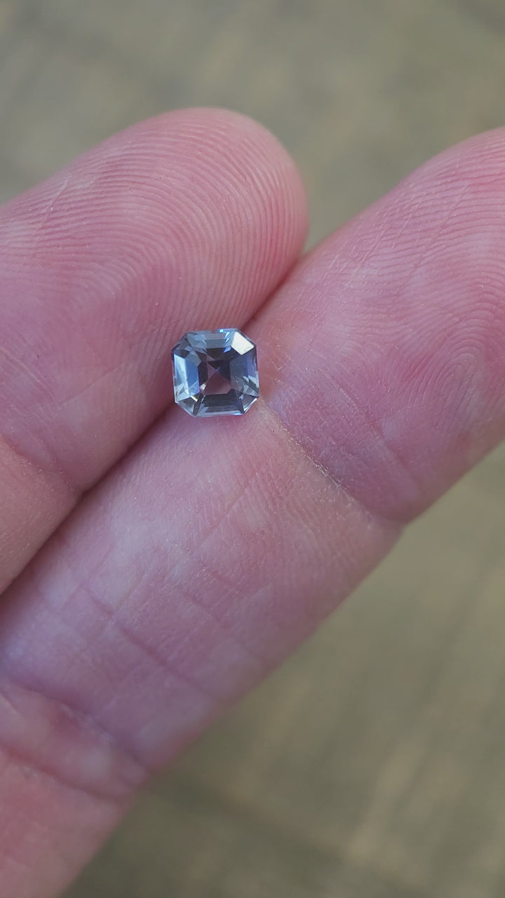 Video showcasing a 1.10 carat Tanzanite gemstone in Asscher cut, highlighting its teal, blue-green, and purple colors under varying light angles for a dazzling display.