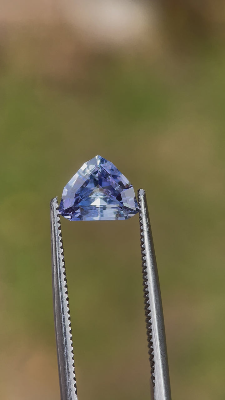 A 360-degree view of a 1.77-carat sapphire with a custom mix shield cut, featuring lavender and powder blue hues. The video highlights the gem’s unique shape and untreated origin, with dimensions of 6.99mm by 8.73mm by 4.03mm, sourced from Sri Lanka.