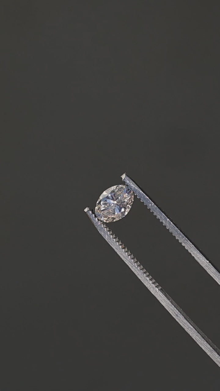 1.23ct champagne oval brilliant cut diamond from Canada rotating in gem tweezers under direct sunlight showing off sparkle and brilliant faceting.