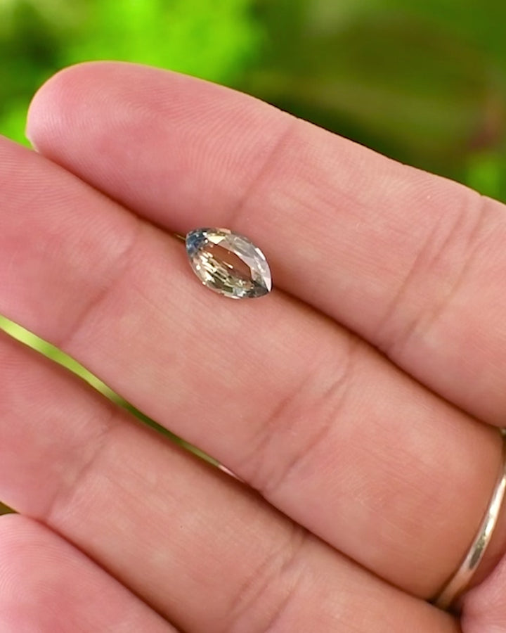 video of Close-up of 1.58CT parti sapphire resting on fingertip, revealing yellow and blue color zoning with exceptional brilliance and clarity, ethically sourced untreated sapphire from Sakaraha, Madagascar.