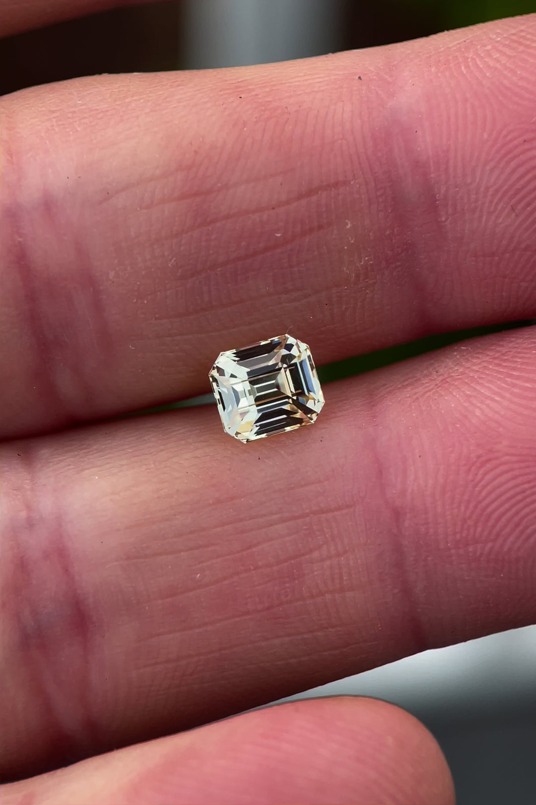 A rotating view of the pastel canary yellow sapphire, weighing 1.43 carats, as it catches light from various angles. The octagonal step cut facets glisten, revealing the gem's pastel hue and brilliance.