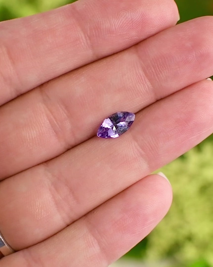Video of 1.15 carat lavender and purple sapphire balanced on a fingertip, revealing its marquise shape and sparkling mixed cut reflections, ethically sourced untreated sapphire from Sakaraha, Madagascar.