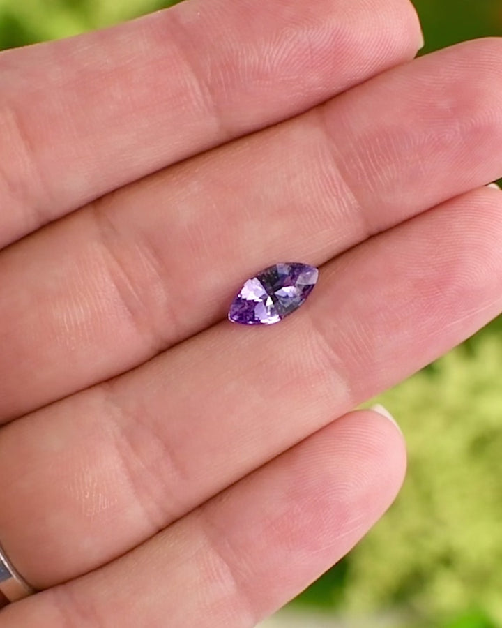 Video of 1.15 carat lavender and purple sapphire balanced on a fingertip, revealing its marquise shape and sparkling mixed cut reflections, ethically sourced untreated sapphire from Sakaraha, Madagascar.