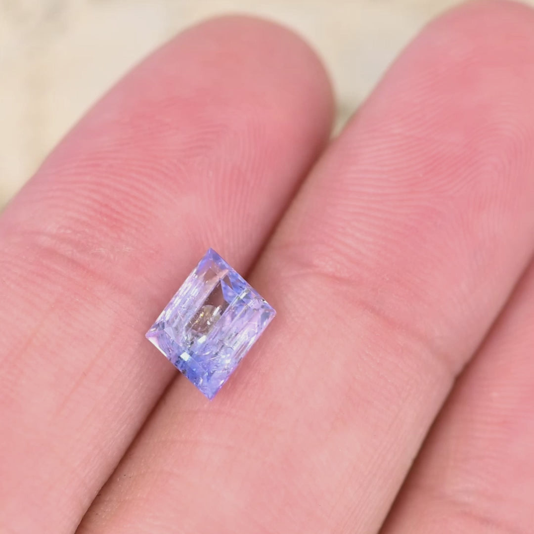 1.67 carat emerald cut Tanzanite video rotating under light showing mermaid purple blue green color shift and natural untreated clarity from Tanzania