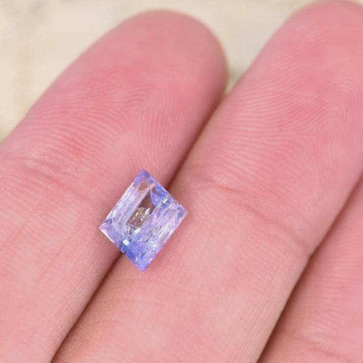 1.67 carat emerald cut Tanzanite video rotating under light showing mermaid purple blue green color shift and natural untreated clarity from Tanzania