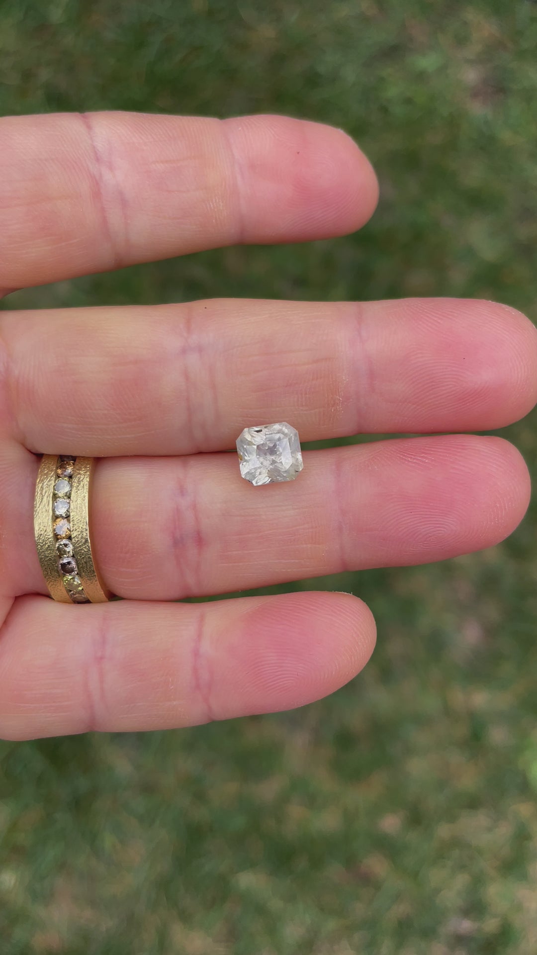 Detailed video showcasing the light reflections and unique facets of a 3.60 carat custom radiant-cut sapphire with earthy pale yellow, gray, and blue hues.