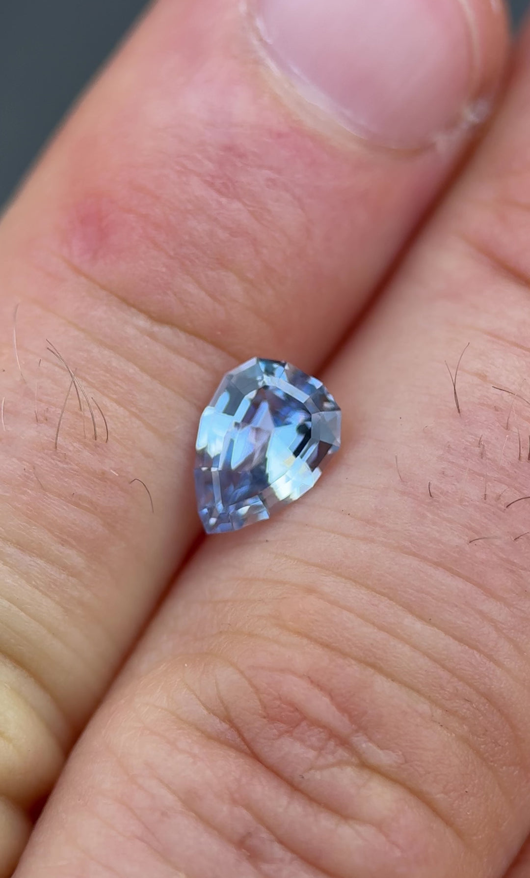 Cornflower and powder blue sapphire weighing 1.67 carats shown on fingertip under natural lighting, unheated and sourced from Sri Lanka