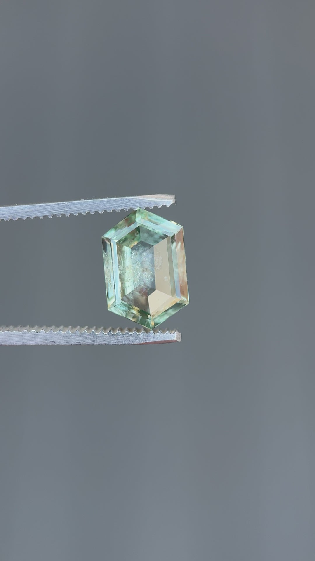 Rotating view of 3.80ct untreated Montana sapphire in step cut hexagon, teal and green hues shimmer in natural light