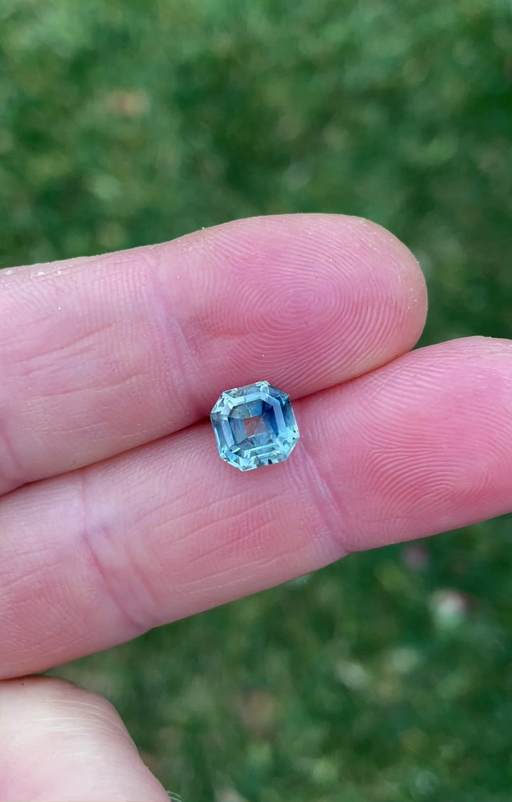 360-degree rotating video of a 2.45-carat parti blue-green sapphire in an antique emerald cut, emphasizing its clarity, vibrant hues, and antique-style proportions.