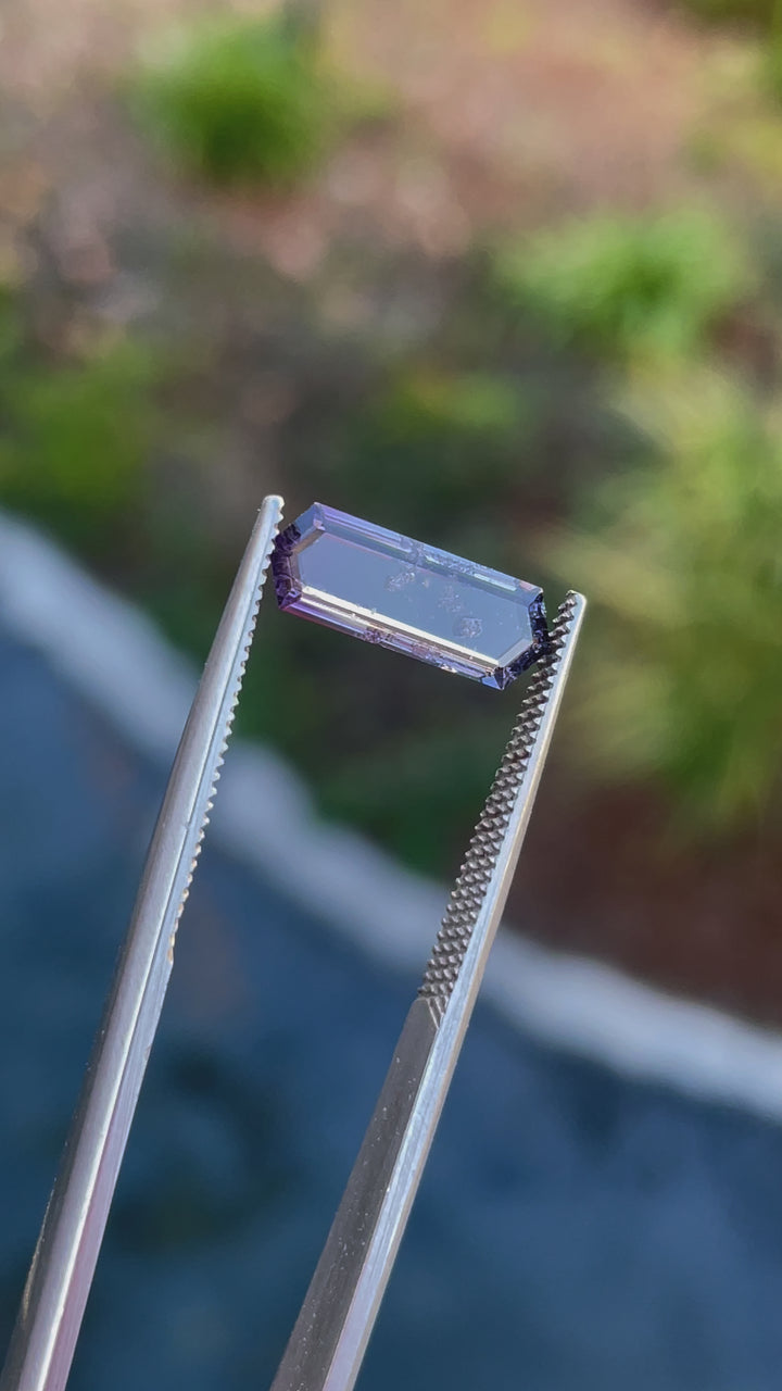 A 360-degree rotating video of a hexagonal step cut spinel gemstone, displaying its purple and pink hues and precise facet arrangement.