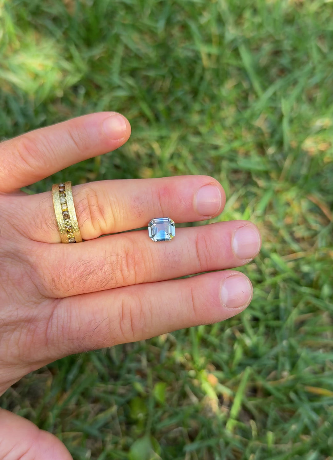 Close-up motion video of a precision emerald cut 4.04CT parti sapphire shifting between light yellow and blue hues as it is turned to display brilliance, clarity, and angular facet pattern.