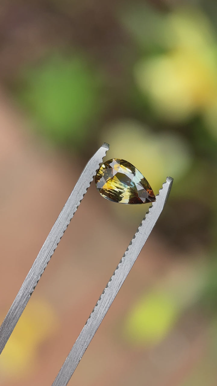 Video of a 1.00-carat pear brilliant sapphire with brown and bluish green hues, rotating to highlight its color contrast and faceting.