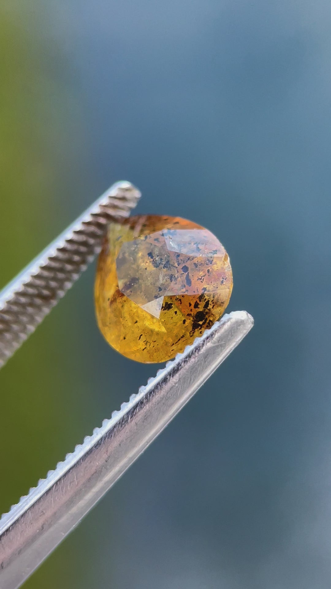 Rotating view of a pear-shaped 3.03-carat sapphire with yellow, orange, and black inclusions, capturing its luster and unique cut.