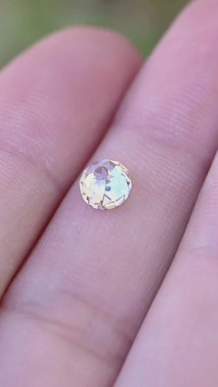 0.99 carat round Mughal cut diamond shown in motion on a hand, revealing its scale and shifting pale champagne, white and cool reflections.